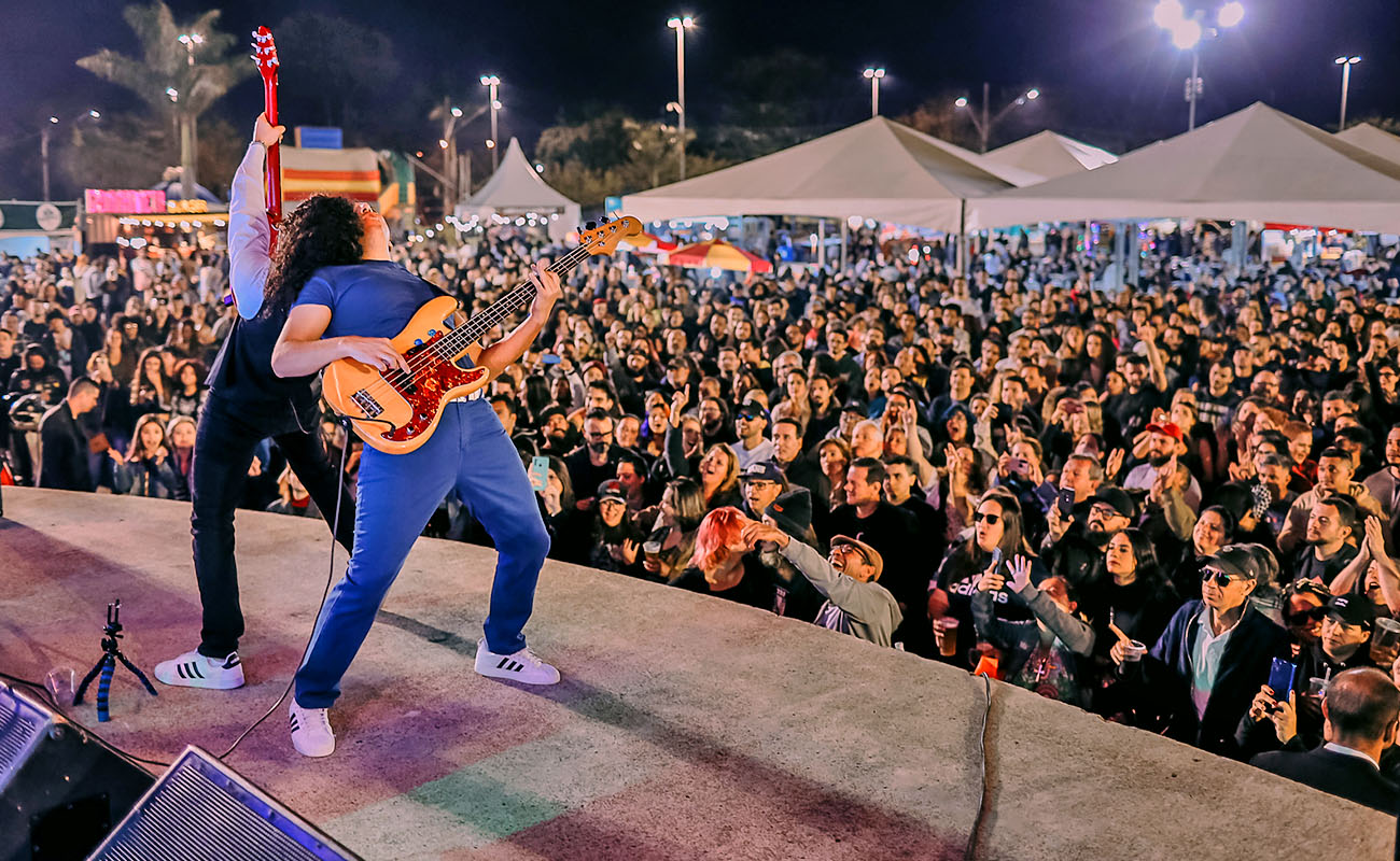 Foto de dois músicos no palco com milhares de pessoas assistindo