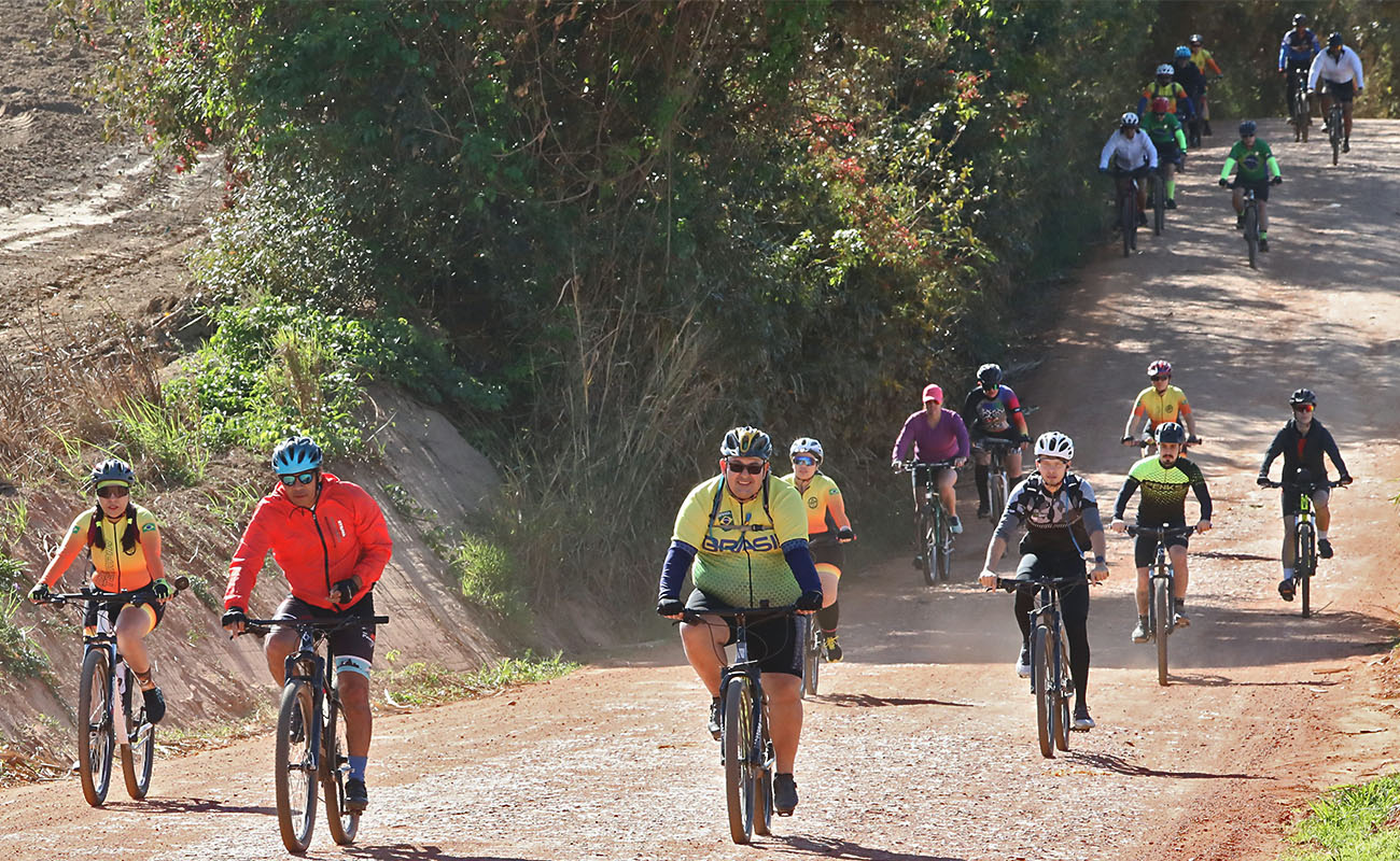 Foto de diversos ciclistas participando do passeio numa estrada de terra