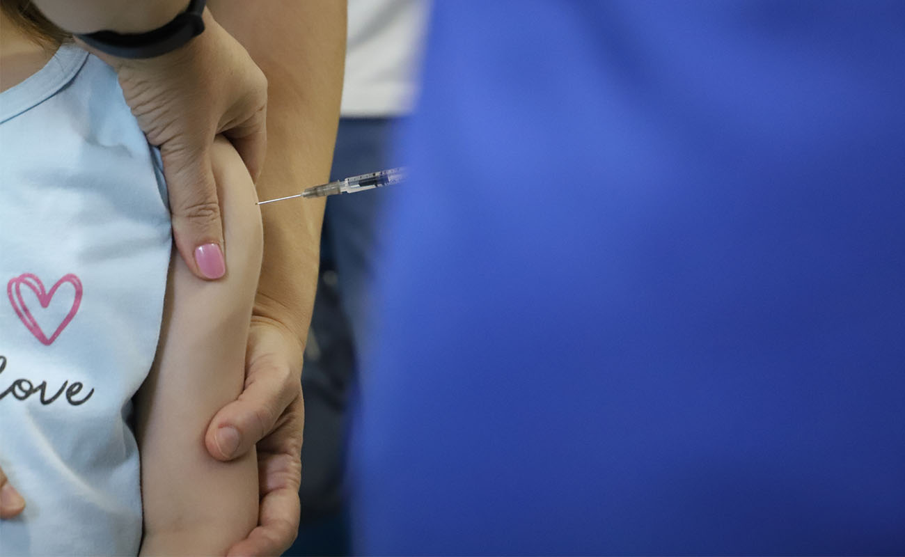 Foto do braço de uma criança sendo vacinada pela enfermeira