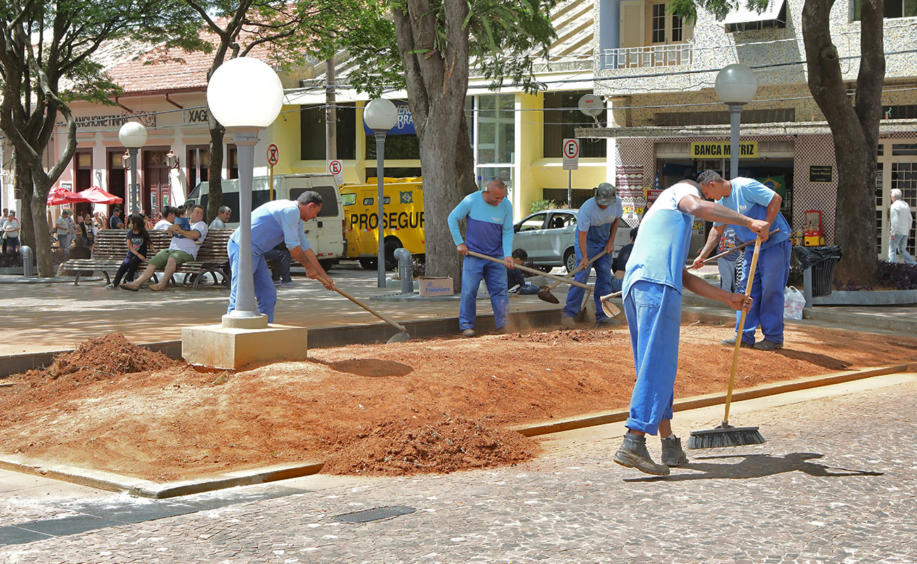 Foto de funcionários públicos fazendo manutenção no jardim da Praça Padre Miguel