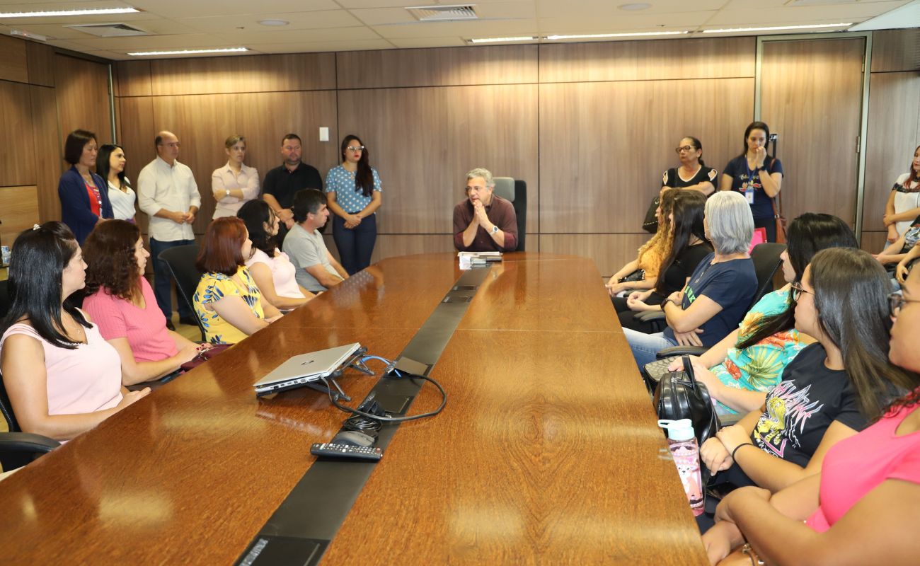 Imagem mostra o prefeito Guilherme Gazolla junto aos novos servidores públicos municipais, sentados em volta de uma mesa, na sala de reuniões do gabinete os novos servidores.