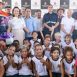 Imagem colorida mostra autoridades junto a crianças durante evento
