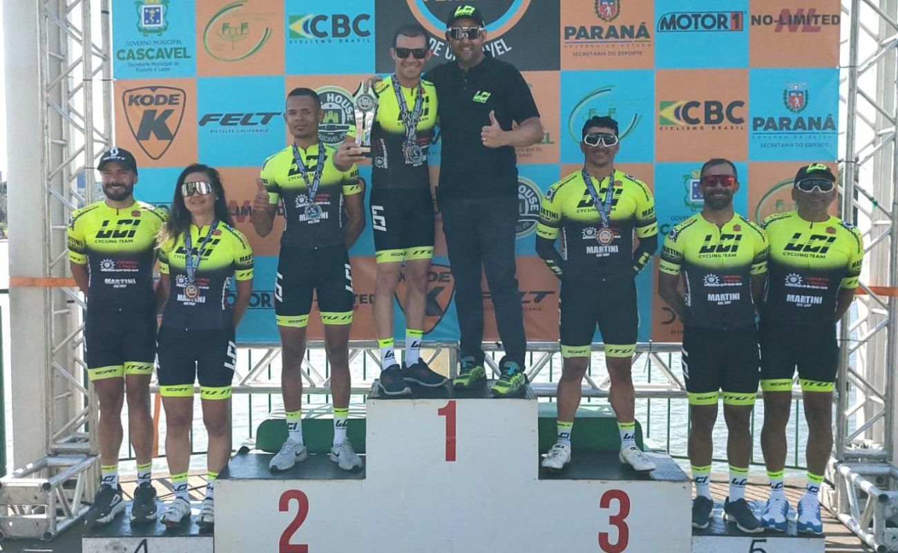 Imagem mostra os atletas da equipe de ciclismo ganhadores da prova no pódium.