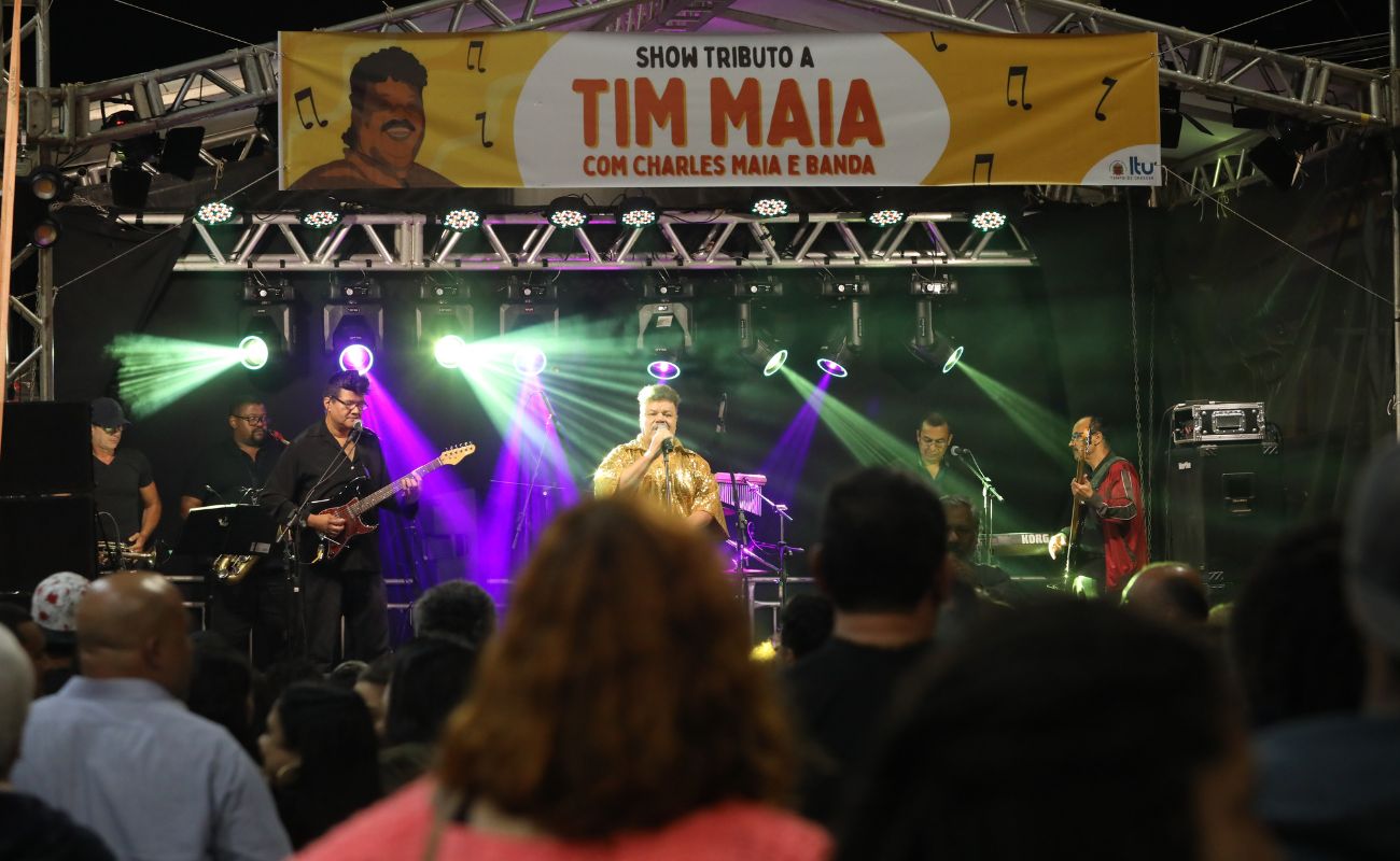 Imagem mostra o cantor Charles Maia, cover do cantor Tim Maia se apresentando no palco. Público de costas para a foto, vendo o show, uma das atrações gratuitas oferecidas pela Prefeitura de Itu.