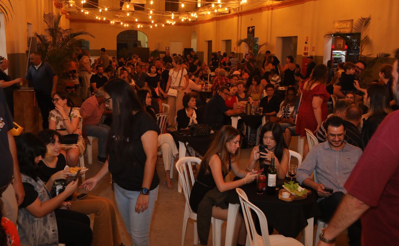 Imagem mostra diversas pessoas sentadas e em pé em um momento de descontração durante as apresentações gratuitas no Mercadão. O evento é primeiro da série Empório Cultural.