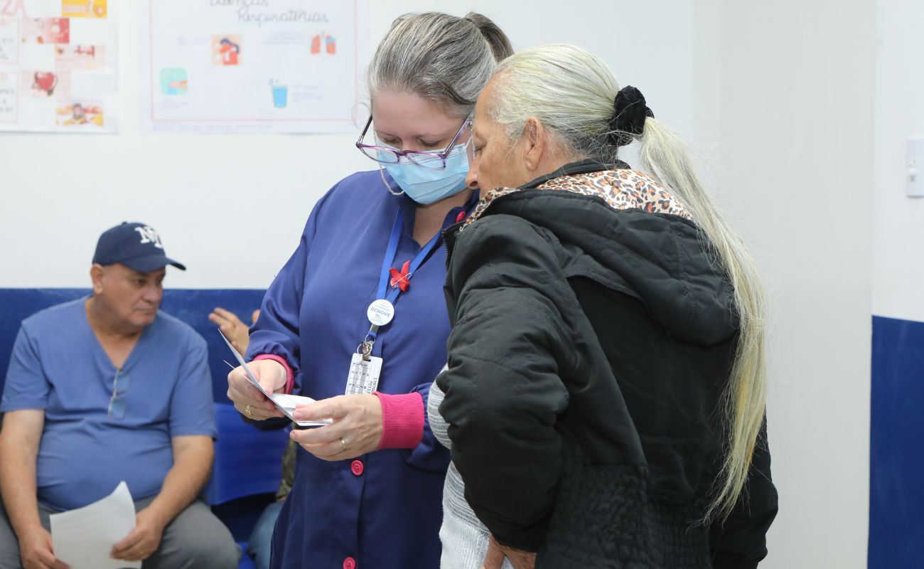 Imagem mostra uma enfermeira realizando o atendimento junto a uma paciente, no Programa Zera Fila.