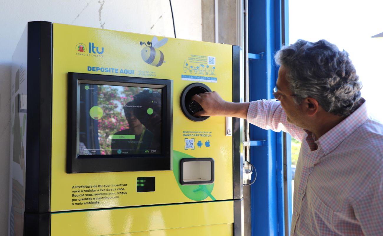 Imagem mostra o prefeito Guilherme Gazzola utilizando uma das máquinas de reciclagem, instalada no Paço Municipal.