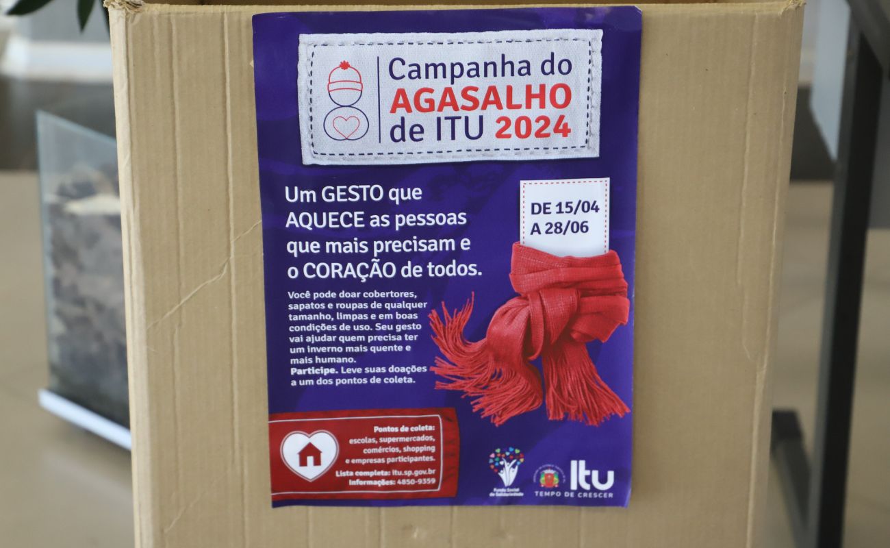 Imagem mostra uma caixa com informações sobre a campanha do agasalho, indicando um dos pontos de arrecadação.