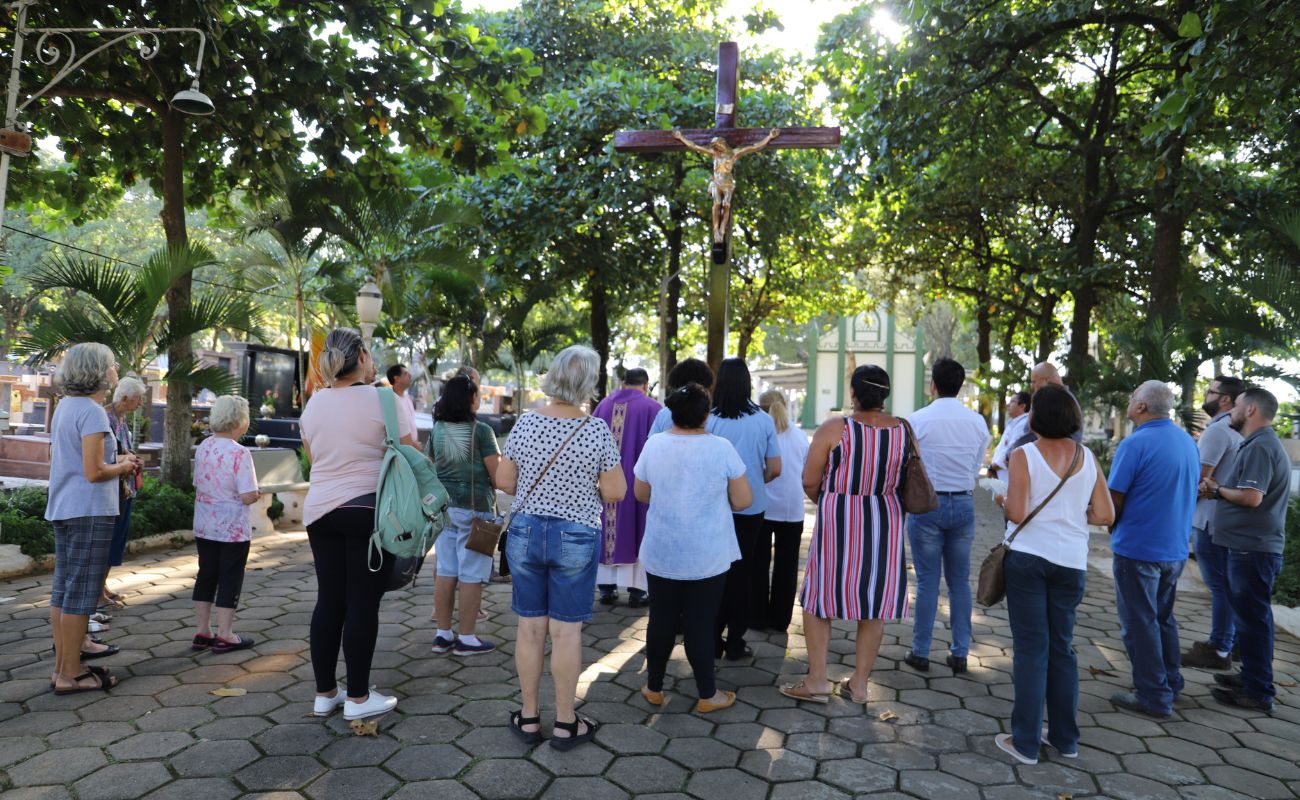Imagem mostra pessoas de costas olhando para um crucifixo no Cemitério Municipal, em evento alusivo ao Dia das Mães anterior.