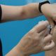 Foto mostra um braço recebendo uma dose da vacina de Covid pelas mãos de uma enfermeira em um dia de vacinação.