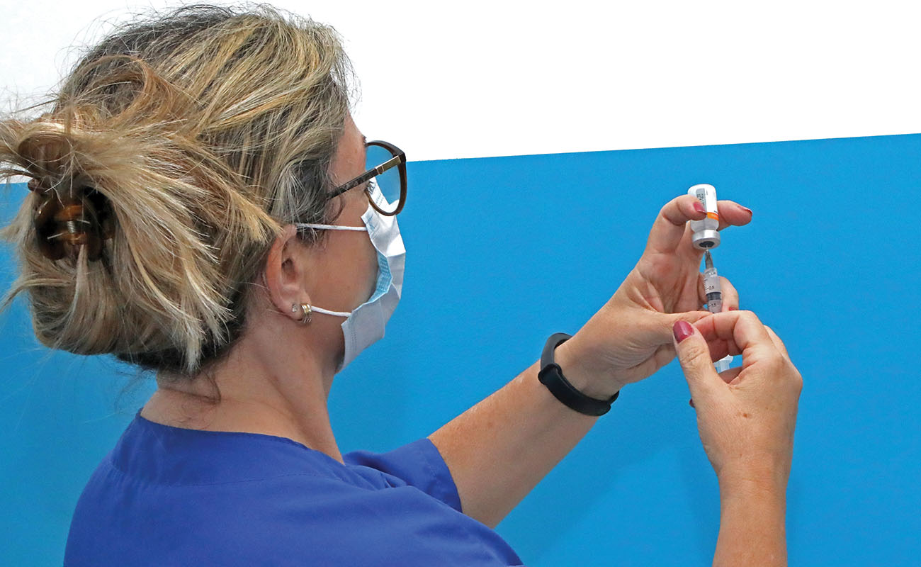 Fotografia mostra a imagem de uma enfermeira em uma das Unidades Básicas de Saúde preparando uma dose da vacina