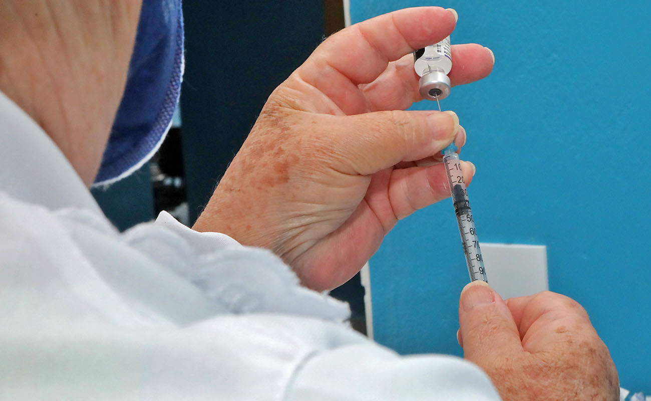 Foto de uma enfermeira aspirando uma ampola de vacina
