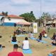 Imagem de pessoas sentadas em tapetes de yoga prontos para a realização da prática