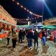 Foto da feira noturna com várias pessoas a noite prestigiando as barracas com comerciantes
