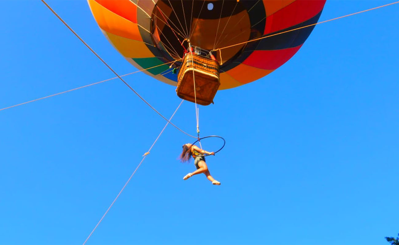 Foto de artista pendurada em um balão dançando no ar