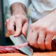 Foto de um açougueiro cortando um pedaço de carne