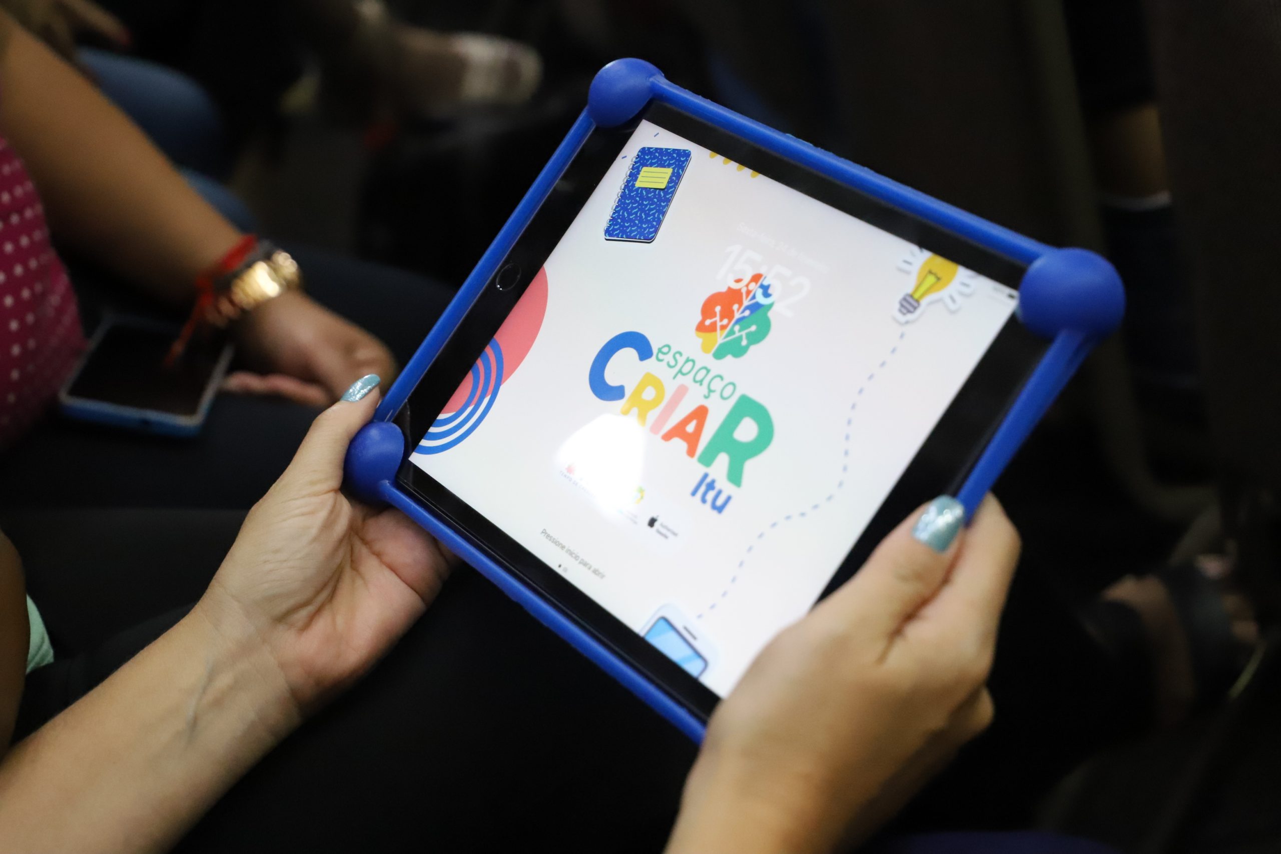Imagem colorida mostra as mãos de uma pessoa segurando um tablet.