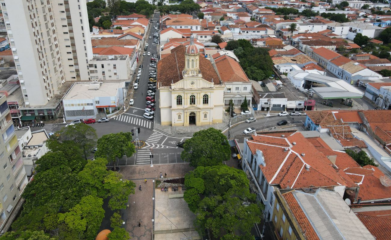 Imagem mostra a cidade vista através de um drone, onde aponta a Praça e a Igreja da Matriz.