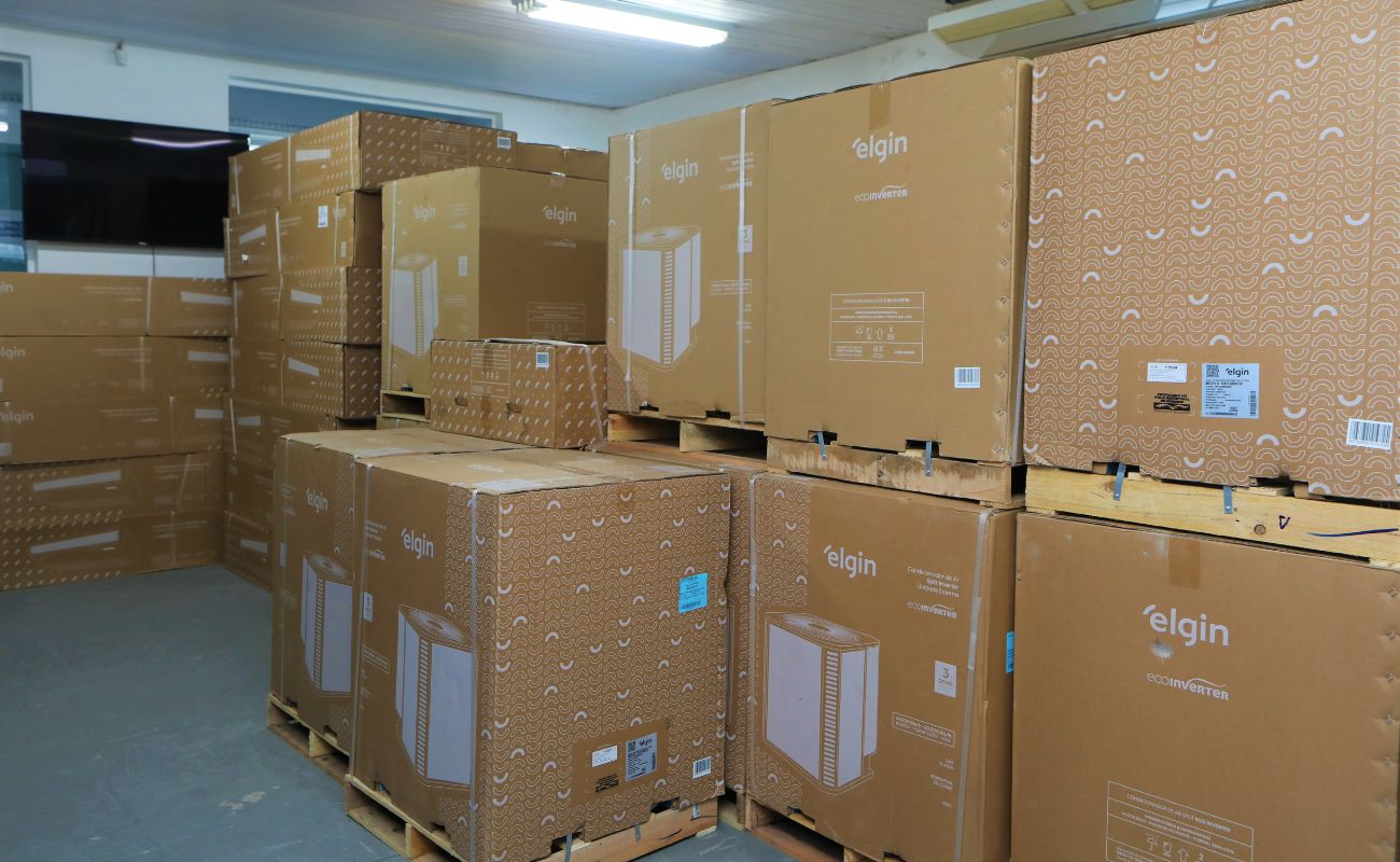 Imagem mostra sala onde estão armazenados os aparelhos de ar condicionados em caixas de papelão.