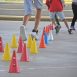 Imagem mostra jovens correndo ao redor de cones coloridos, um dos treinamentos realizados nos esportes com inscrições abertas.