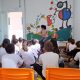 Imagem mostra crianças de costas ouvindo uma história contada por uma mulher. O local é o Centro Ituano de Letras e Artes, que completa 1 ano de exitência