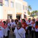 Imagem mostra pessoas caminhando pelas ruas da cidade, no tradicional desfile do divino. Todas vestidas com camisas brancas e lenços vermelhos no pescoço, segurando uma bandeira vermelha estampada o divino Espírito Santo.