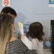 Imagem mostra dois adultos com uma criança no colo da mãe, sendo atendidos em uma das unidades básicas de saúde para completar o esquema vacinal de prevenção contra a Covid.