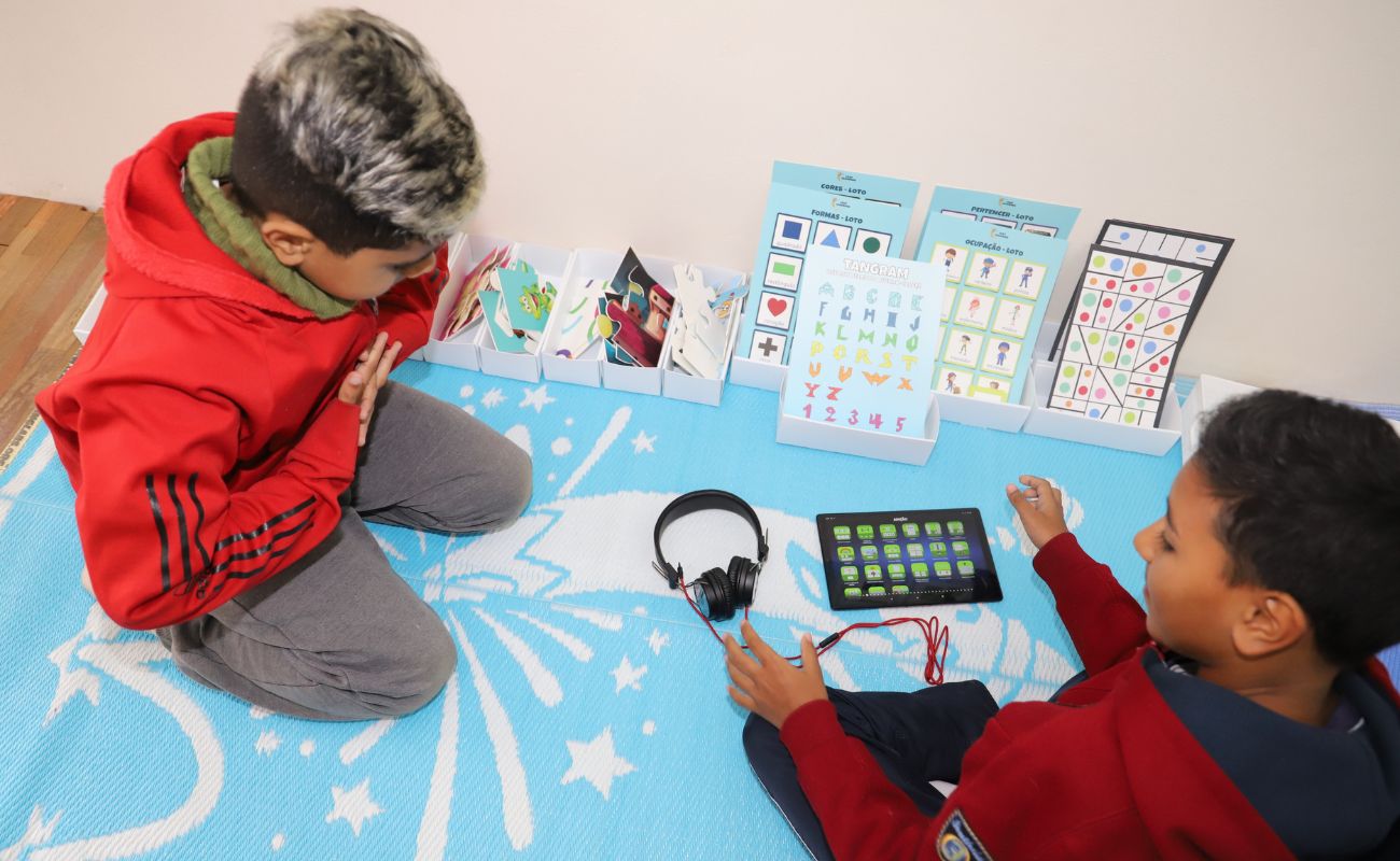 Imagem mostra duas crianças sentadas com um tablet no laboratório Leap Learning