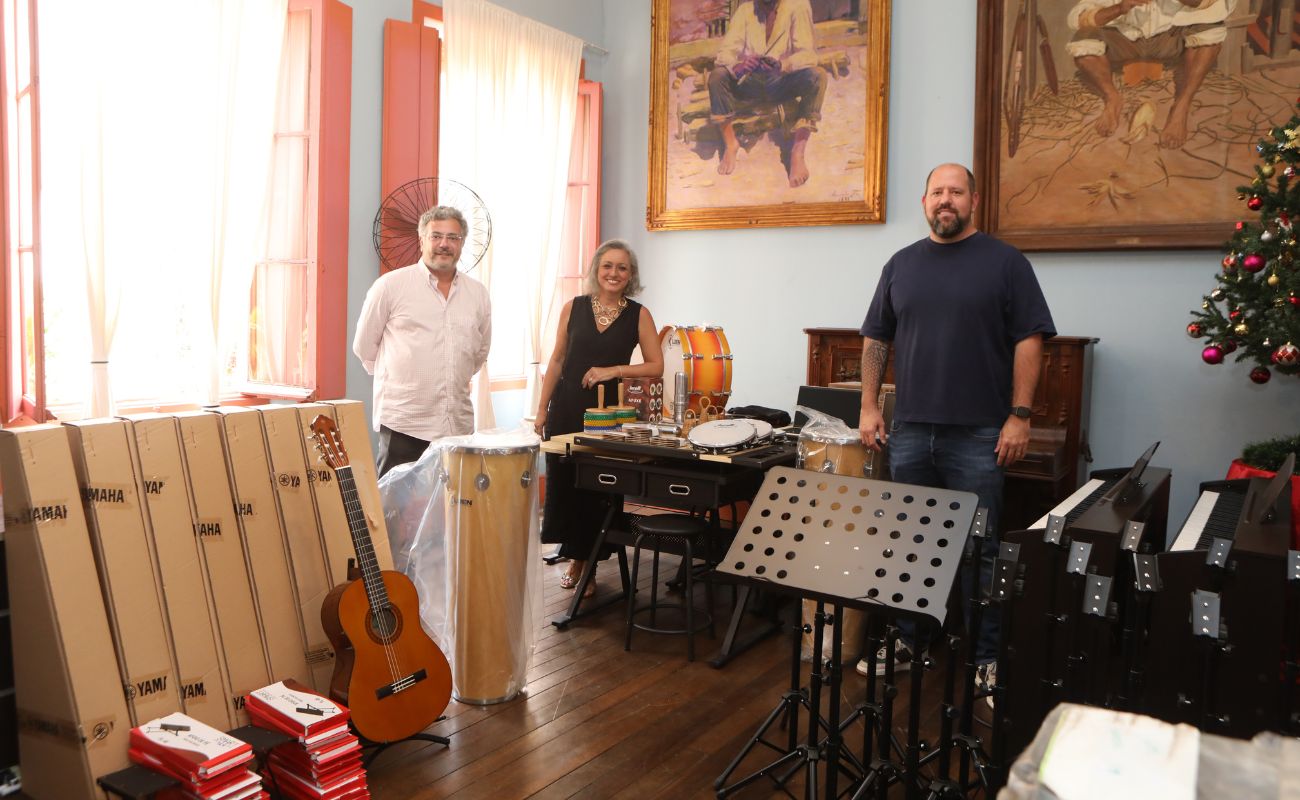 Imagem mostra o prefeito Guilherme Gazzola com Mario Sergio Albuquerque (Tomorrowland Brasil) e Adriane Menna (Instituto Tecendo Infâncias) em momento de doação de instrumentos.