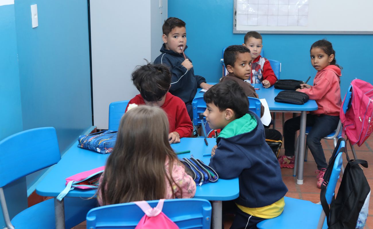 Imagem mostra crianças sentadas em sala de aula.