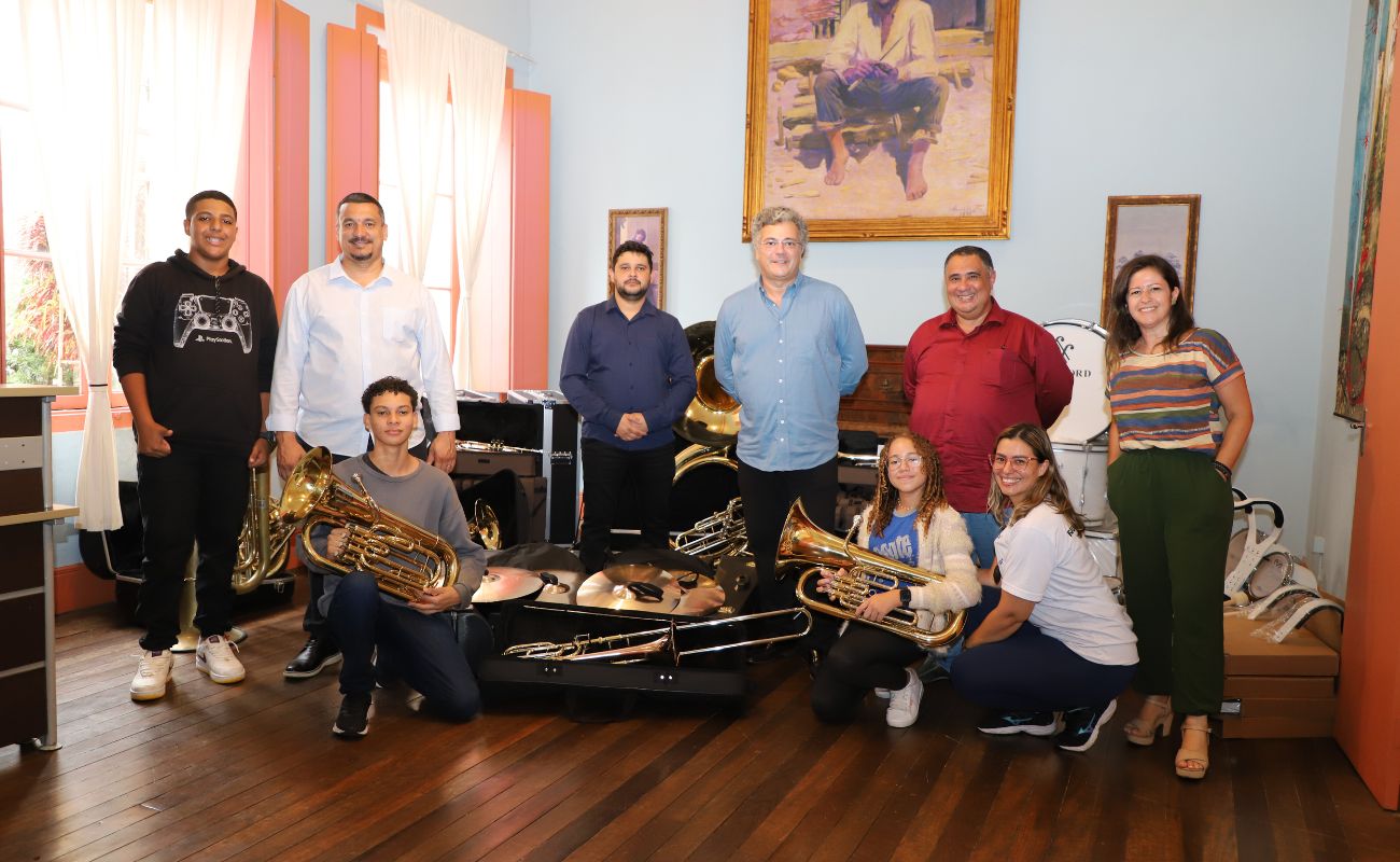 Imagem mostra o prefeito Guilherme Gazzola junto a autoridades em momento de entrega de novos instrumentos à Banda Marcial Municipal.