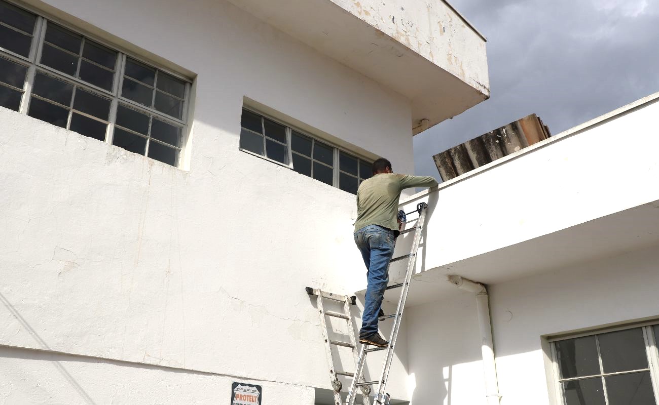 Imagem mostra um prestador de serviço em cima da escada realizando serviços na reforma da UBS 4 localizada no Jardim Vitória.