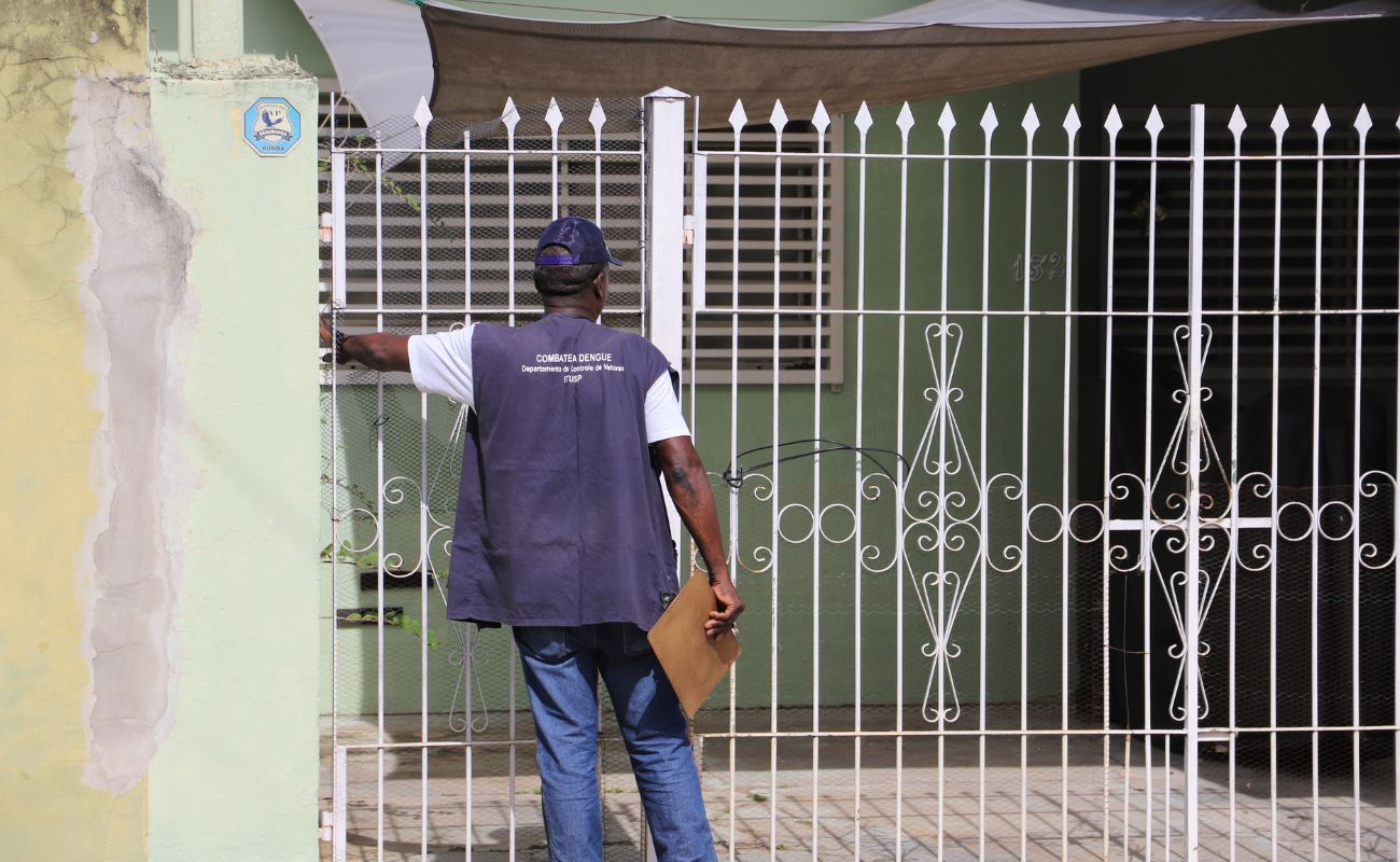 Imagem mostra um agente no combate a dengue de costas, tocando a campainha de uma residência, essa é uma das ações realizadas na mobilização contra a dengue