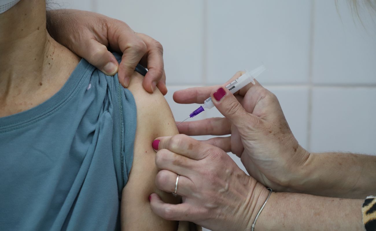 Imagem mostra um braço em foco recebendo vacina