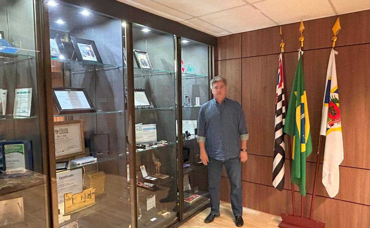 Imagem mostra o prefeito Guilherme Gazzola em seu gabinete, a frente de todos os prêmios recebidos ao longo da gestão Guilherme Gazzola.
