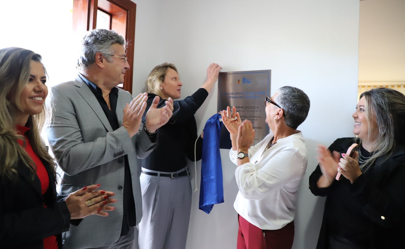Imagem mostra o prefeito Guilherme Gazzola junto das secretárias de Saúde, Janaina Guerino e Promoção Social Alzira Guimarães, em momento de decerramento da placa de inauguração da Casa de Apoio às Mulheres Vítimas de Violência.