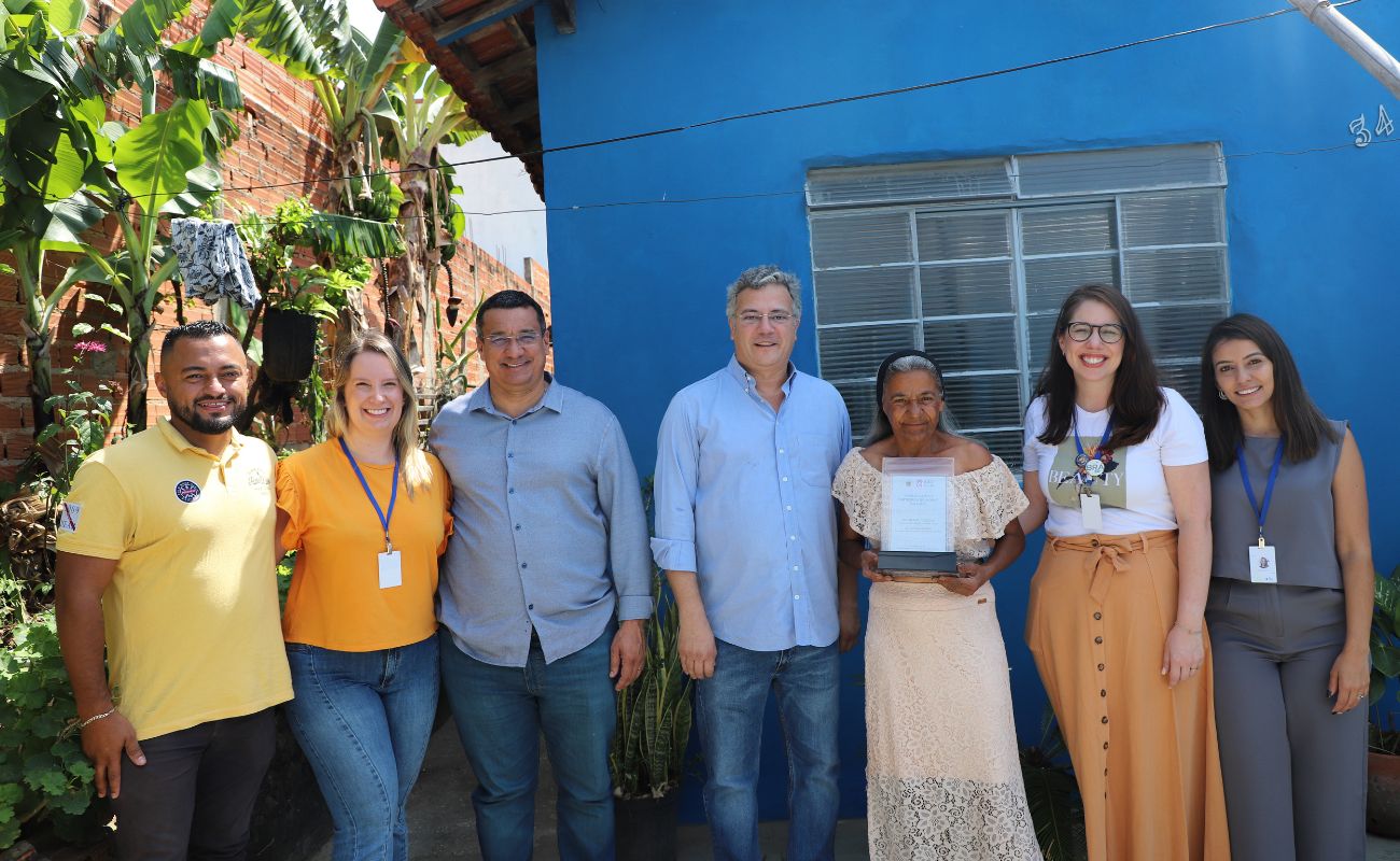 Imagem mostra o Prefeito Guilherme Gazzola, o Secretário de Planejamento Gilmar Pereira, equipe e a senhora que teve sua residência contemplada pelo Programa Morar Melhor.