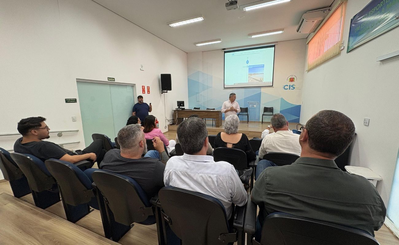 Imagem mostra o prefeito Guilherme Gazzola em pé, conversando com membros da futura gestão, estes todos sentados.